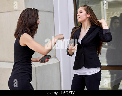 Zwei junge Frauen mit einem lockeren Gespräch und lächelnd halten Handys Stockfoto