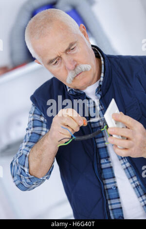 Senior woman Befestigung elektrischen Stecker Stockfoto