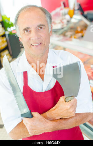 Metzger holding Messer und Beil, Arme verschränkt Stockfoto