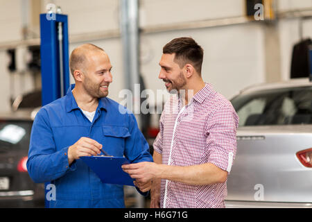 Automechaniker mit Zwischenablage und Mann an dem Auto Shop Stockfoto