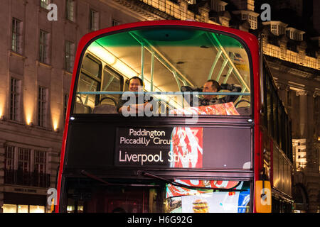 Nachtzeit Busse fahren durch einen hell beleuchteten und beleuchtete Piccadilly Circus in central London, UK Stockfoto