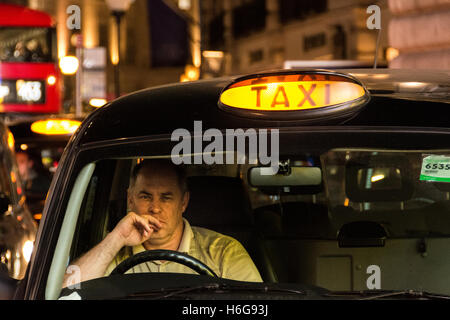 Ein ermüdeter und müde aussehender Nachtfahrer mit einem schwarzen Taxi im Londoner West End
