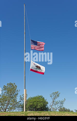 USA und California Fahnen auf Halbmast auf einem Hügel oben mit blauem Himmelshintergrund Stockfoto