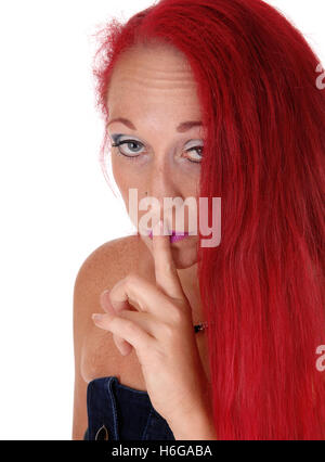 Nahaufnahme einer roten dunkelhaarige Frau mit ihrem Finger über den Mund, mit langen roten Haaren, für weißen Hintergrund isoliert. Stockfoto