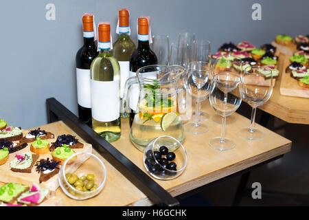 Holztablett Vorspeisen bei einem Bankett auf einem dekorierten Tee Tisch mit roten und weißen Wein und Karaffe mit fruchtigen Getränk mit Minze und Zitrone. Wunderschön dekoriert Tischset im Restaurant. Stockfoto