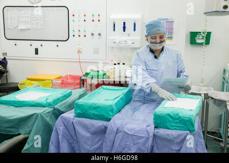 Eine Krankenschwester in Scrubs prüft die sterile Ausrüstung vor dem Öffnen in ein Krankenhaus-OP-Saal Stockfoto