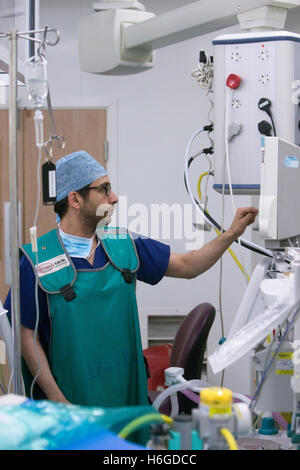 Ein Anästhesist prüft einen medizinischen Tropf während einer Operation in einem Krankenhaus-Theater Stockfoto