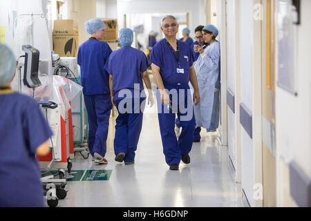 Ärzte, Krankenschwestern und Chirurgen in einem NHS Krankenhausflur tragen scheuert Stockfoto