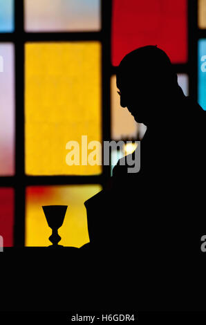 Priester in der Silhouette, unkenntlich, während die Eucharistie einer katholischen Messe Stockfoto