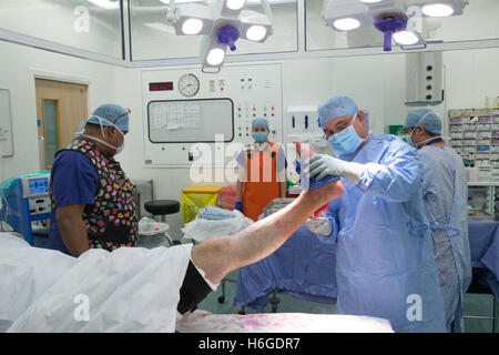 Ein Chirurg und Personal vorbereiten ein Patienten für eine Operation vor der Durchführung einer offenen Reposition und Osteosynthese des linken Sprunggelenks Stockfoto