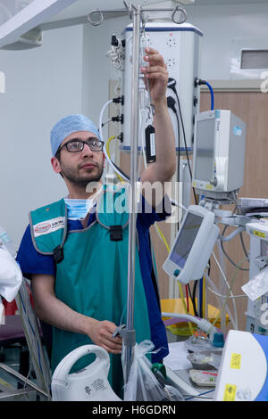 Ein Anästhesist prüft einen medizinischen Tropf während einer Operation in einem Krankenhaus-Theater Stockfoto