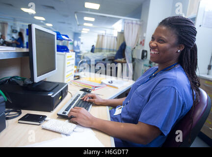 Krankenschwester an einer Workstation in einer Gemeinde, die Beantwortung von Anfragen und medizinische Unterlagen Stockfoto