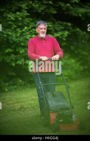 Senior woman Mähen des Rasens in seinem Garten Stockfoto