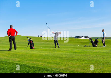 Golfspieler spielen an Thurlestone Golf Club, Devon, an einem Sommertag gegen einen klaren blauen Himmel Stockfoto