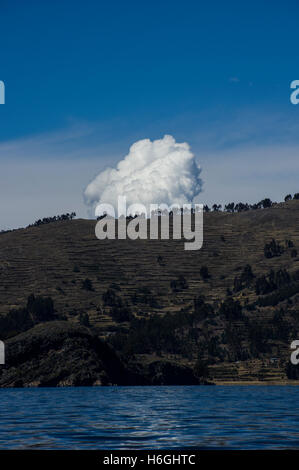 Auffallend weißen Wolken über einem Hügel mit Bäumen vor einem blauen Himmel am Titicacasee, Bolivien. Der See grenzt auch an Peru. Stockfoto