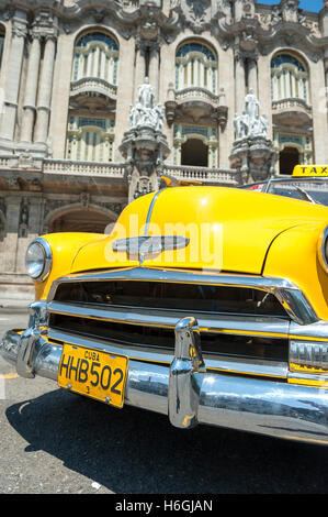 Havanna, Kuba - 13. Juni 2011: Leuchtend gelbe amerikanische Oldtimer steht geparkt vor dem Wahrzeichen große Theater. Stockfoto