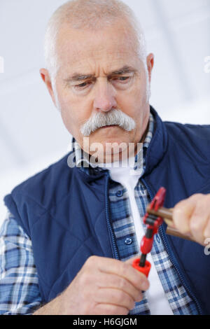 Senior Handwerker versucht, etwas zu beheben Stockfoto