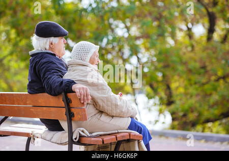 Älteres paar sitzen auf Bank im Herbst park Stockfoto