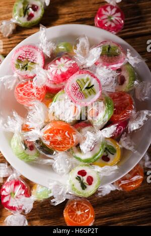 Vertikale Foto mehrere Bonbons mit Fruchtgeschmack und Obst-Motiven mit orangenen im Fokus. Jedes Bonbon ist in Zellophan und er Stockfoto