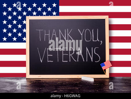 Grußkarte der Handschrift Text danke Veteranen ist in Tafel mit Flagge USA und Kreide auf Craq geschrieben. Stockfoto