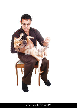 Ein Hispanic Mann hat seinen Sharpei Welpen Hund auf seinem Schoß und spielt mit seinem besten Freund, sitzend auf einem Stuhl für weißen Hintergrund. Stockfoto