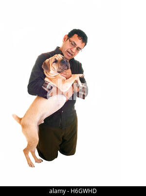 Ein Hispanic Mann kniet auf dem Boden und mit seinem besten Freund in seinen Armen, spielen mit dem Hund, für den weißen Hintergrund. Stockfoto