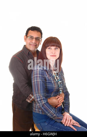 Eine nette Paare dort vierzig, sie sitzen auf einem Stuhl und er umarmt sie von hinten, für weißen Hintergrund. Stockfoto