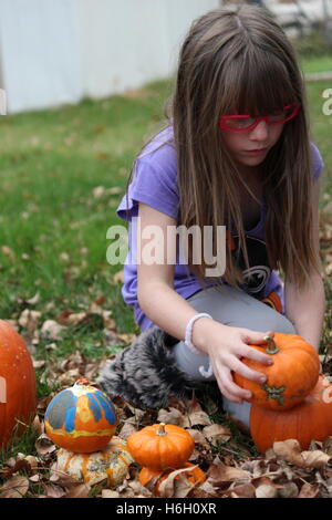 Junge Kind oder Mädchen stapeln Kürbisse auf den Herbst Blätter auf dem Boden Stockfoto