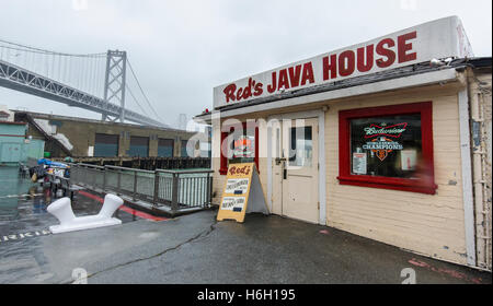 Red es Java House auf der Embarcadero in San Francisco, sitzt im Regen mit der Bay Bridge im Hintergrund. Stockfoto