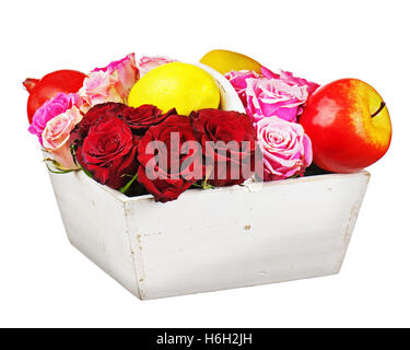 Blumen-Arrangement von roten Rosen und Obst in hölzernen Korb isoliert auf weißem Hintergrund. Closeup. Stockfoto