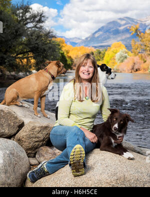 Outdoor-Porträt von attraktiven Frau mit ihren drei Hunden neben den Arkansas River; Salida; Colorado; USA Stockfoto