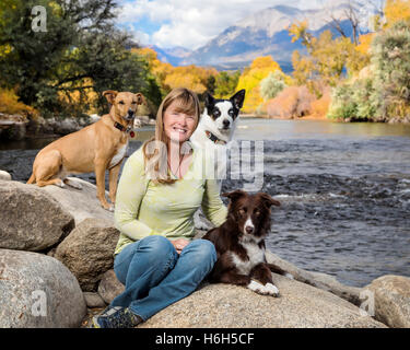 Outdoor-Porträt von attraktiven Frau mit ihren drei Hunden neben den Arkansas River; Salida; Colorado; USA Stockfoto