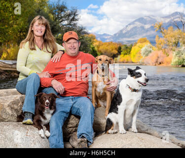 Outdoor-Porträt von Ehepaar mit ihren drei Hunden neben den Arkansas River; Salida; Colorado; USA Stockfoto