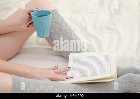 Frau am Bett Lesebuch entspannen und lerne Kaffee Stockfoto