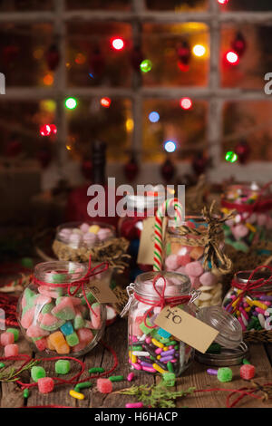 Verschiedene Süßigkeiten in Gläsern für Weihnachtsgeschenke auf rustikalen Holztisch Stockfoto