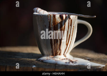 Sehr chaotisch heiße Schokolade mit Schlagsahne und Schokolade Sauce überlaufen einen Becher set auf Baumstumpf Stockfoto