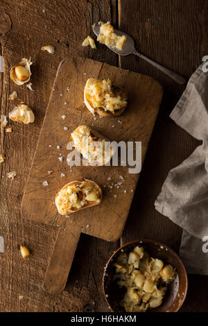 Crostini mit gestampften geröstetem Knoblauch auf rustikalen Schneidebrett Stockfoto