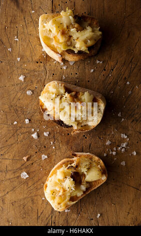 Crostini mit gestampften geröstetem Knoblauch auf rustikalen Schneidebrett Stockfoto