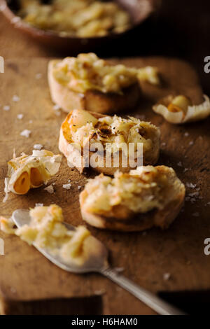 Crostini mit gestampften geröstetem Knoblauch auf rustikalen Schneidebrett Stockfoto