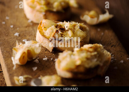 Crostini mit gestampften geröstetem Knoblauch auf rustikalen Schneidebrett Stockfoto