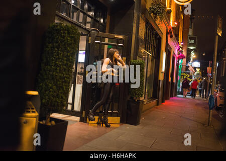 Nachtleben in Temple Bar Viertel von Dublin, Republik Irland. Eine junge Frau erzählt auf Handy vor einer Bar.  Die eine Stockfoto