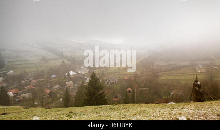 Späten nebligen Herbstmorgen in einem Dorf. Erster Schnee in den Bergen Stockfoto