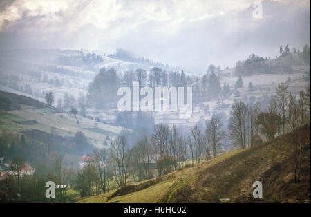 Späten nebligen Herbstmorgen in einem Dorf. Erster Schnee in den Bergen Stockfoto