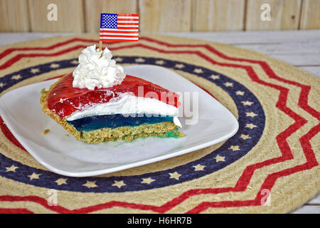 roten und blauen Wackelpudding Torte mit geschlagener Sahne und amerikanische Flagge auf weißen quadratischen Platte Stockfoto