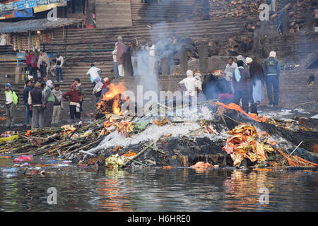 Brennenden Leichen, Asche und Rauch auf den Ghats von Varanasi, Uttar Pradesh, Indien Stockfoto