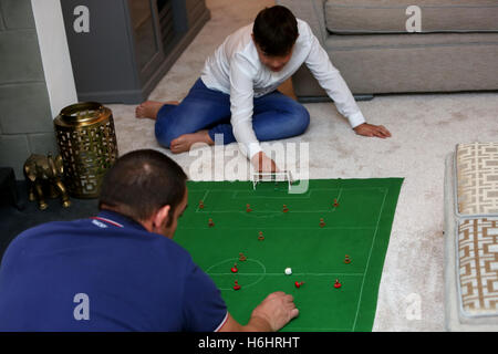 Ein Vater und sein Sohn abgebildet die Subbuteo in Leeds, West Yorkshire, UK Football-Spiel ihre Lounge zu Hause zu spielen. Stockfoto