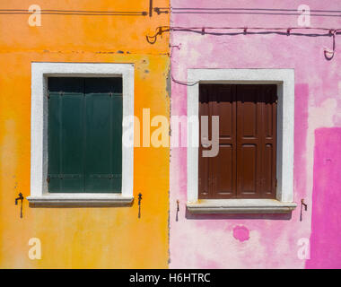 Zwei Fenster mit hölzernen Bildschirm im farbenfrohen Pink und Orange Gebäude Fassade der Burano Stadt, in der Nähe von Venedig Stockfoto