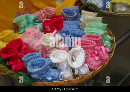 Weidenkorb voller Baby Bootie handgefertigt von einer alten Dame auf einer Seitenstraße in Sorrent Italien gemischte rosa blau Paare Peg gestrickt Stockfoto