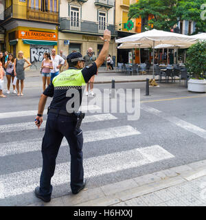 Ein spanischer Polizist regelt den Verkehr auf einen Fußgängerüberweg in Valencia, Spanien Stockfoto