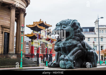 Eine Löwenstatue sitzt gegenüber der Scheintor auf Nelson Street in Liverpool, der größten Bogen seiner Art außerhalb Chinas. Stockfoto